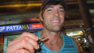 man holding a locust- eating bugs in Thailand