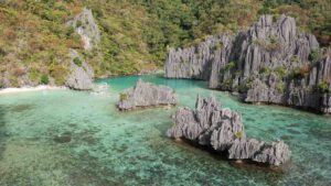 Drone photo of Cadlao Lagoon with dark rock formations and tropical water in El Nido