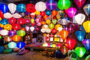A man sits in front of his shop selling lanterns of the date of the Hoi An lantern festival that falls on the full moon