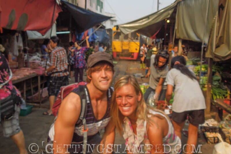 couple at the train market in Bangkok with train coming