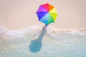 Girl walking on the beach in the Maldives with rainbow umbrella
