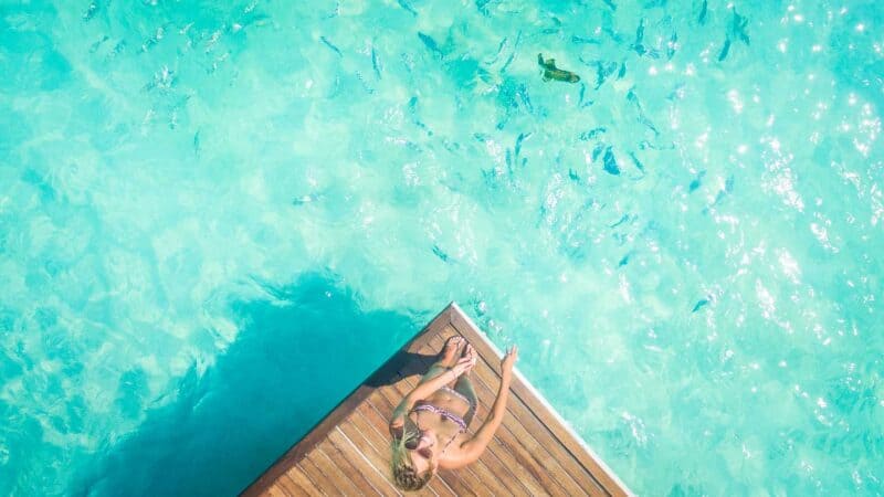 girl feeding the fish from the dock at Summer Island Maldives resort