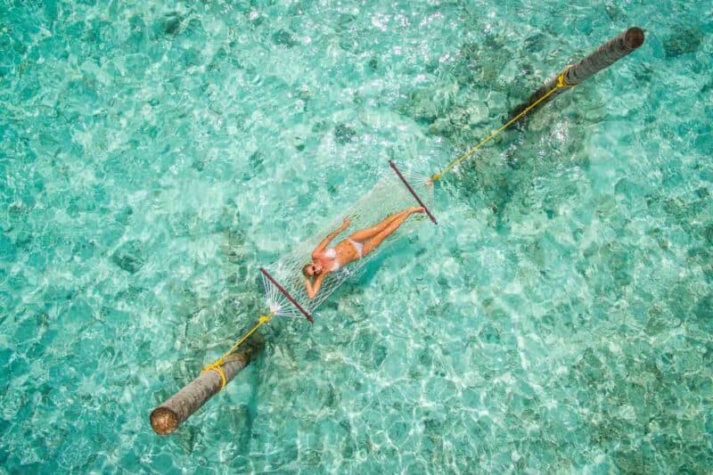 girl in a hammock floating in the middle of the ocean in the Maldives 