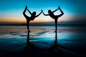 Two girls doing yoga on the beach in Bali