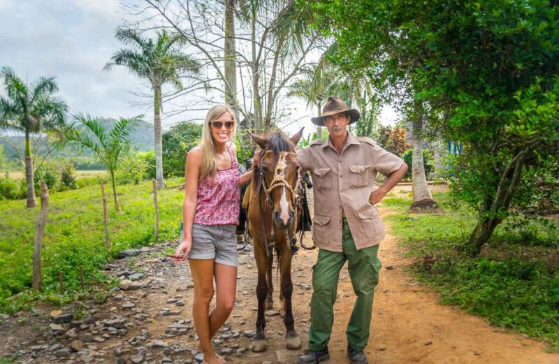 Girl with a horse and guide in Vinales Cuba going through the tobocco fields