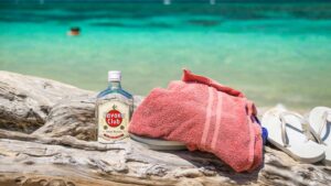 bottle of Havana Club rum and beach towel on the beach in Cuba