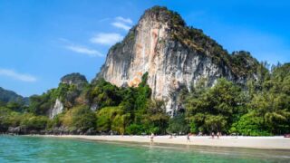 Railay Beach Thailand large exposed rock face white sand beach and tropical waters make for a perfect honeymoon destination