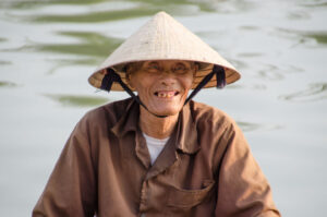 Vietnamese man on a boat in the Mekong Delta with a Vietnamese rice hat