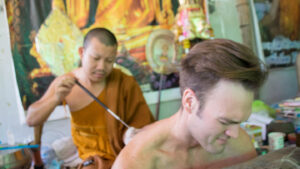 Adam getting his first tattoo by a monk in Thailand