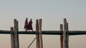 Two monks in red robes walk the U Bein Bridge at Sunrise - Things to do in Mandalay Myanmar