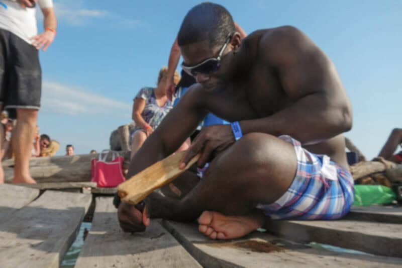 Man carving his name into the wooden planks of the Pelican Bar