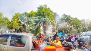 A boy throwing a bucket of water from the back of a truck in Chiang Mai during the songkran festival