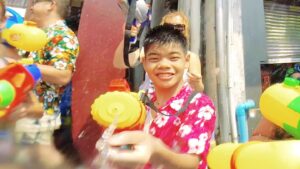 Thai boy with floar shirt squirting the camera at the songkran festival in Chiang Mai Thailand