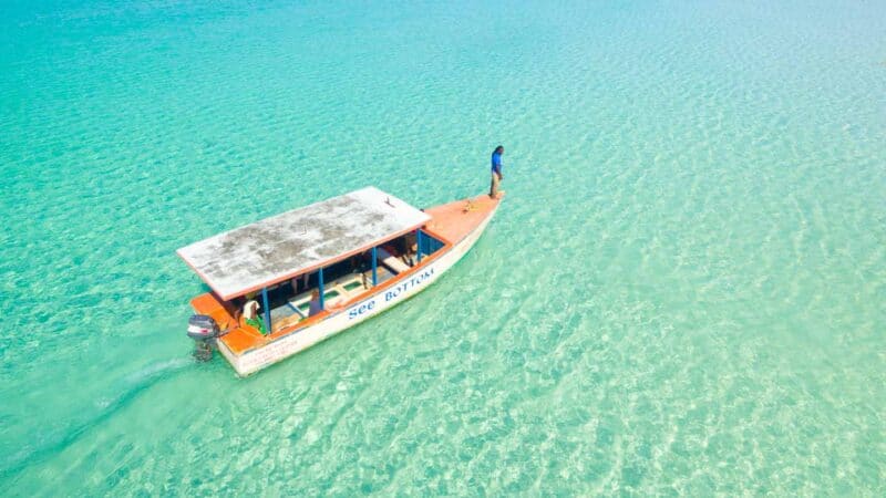 Man standing on the bow of a glass bottom snorkeling tour boat - best things to do in Negril