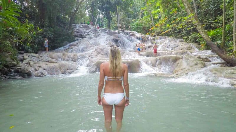 Woman stands in front of Dunn's River Falls in Jamaica preparing to climb the falls