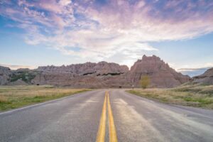 Two lane hwy road in badlands national park in south dakota with rock formation at the end of the road