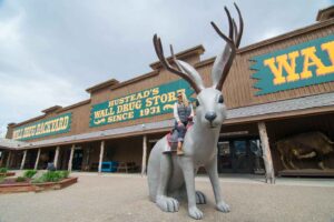 Woman ride large jackalope in the backyard of Wall Drug in Wall South Dakota - A must on any road trip