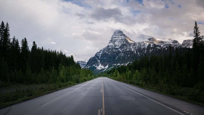 Road with mountains in the background on the Ice Fields Parkway on the drive to Alaska