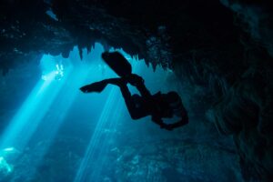 Diver swim around the stalgtites formed at the top of the cenote