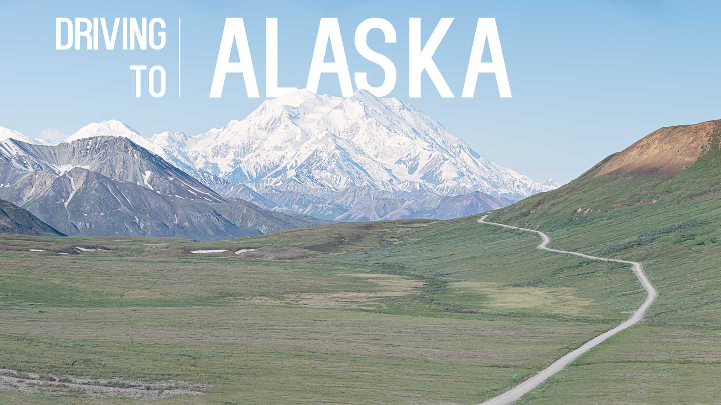 view of the road to the mountains while driving to Alaska - Featured image with white text