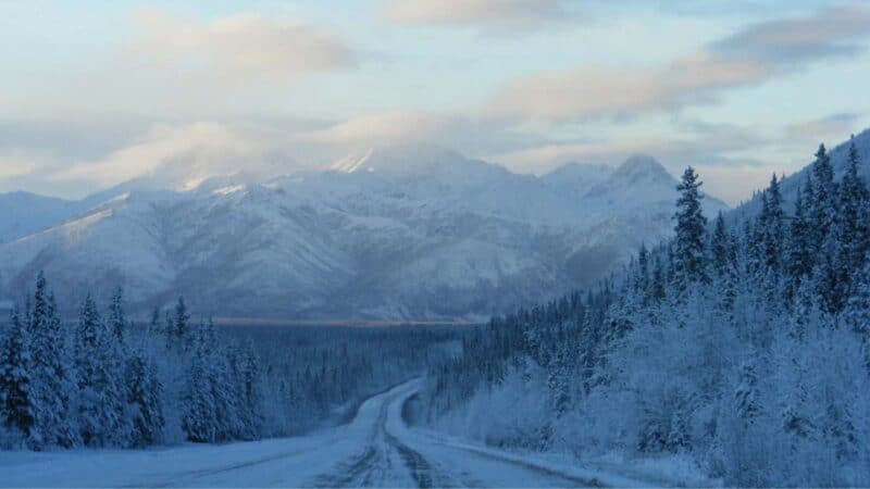 Alaska Highway in winter snow covered with mountains in the background