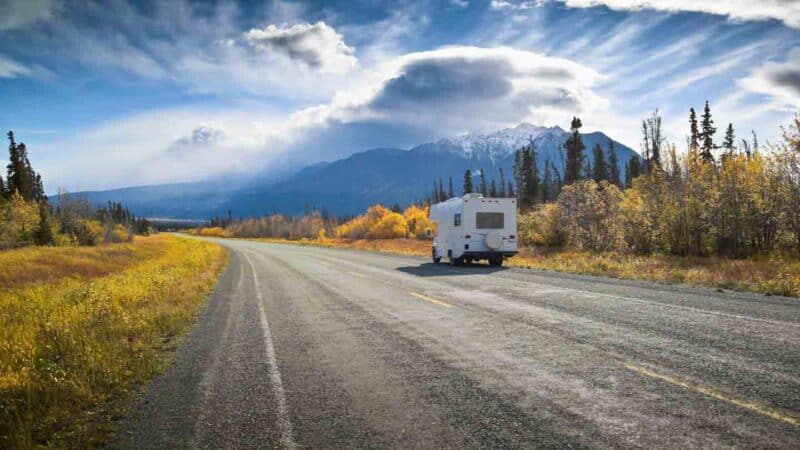 RV driving to Alaska pulled over on the Alcan Highway with mountains in the background