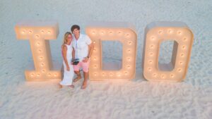 couple standing in front of an "I Do" illuminated statue during the Caribbean's largest vow renewal in Aruba