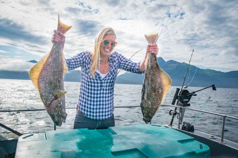 girl holding two halibut fish in Homer Alaska