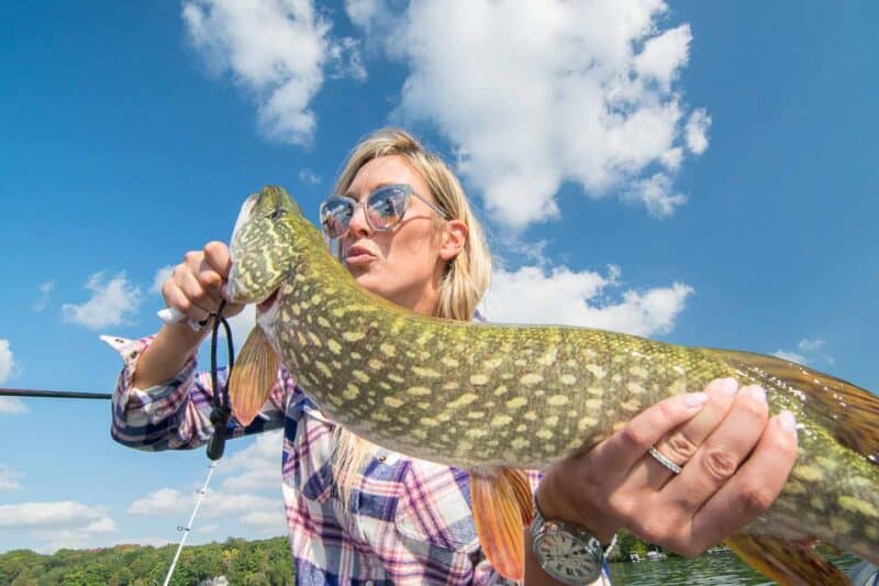 Girl kissing a northern fish in Green Lake Wisconsin 