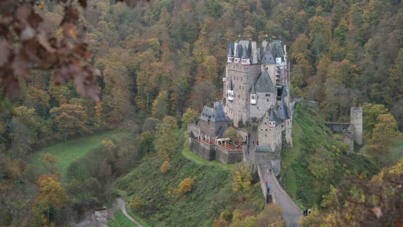 Burg Eltz Viewpoint from walk from parking lot - Leaves in front of the distant castle