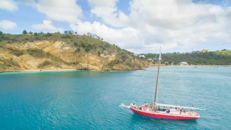 Red sail boat in front of little bay - - Best things to do in Anguilla