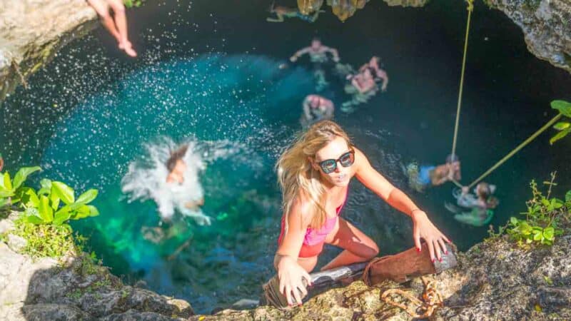 woman climbing out of Cenote Calavera on a ladder - One of the best Cenotes in Tulum and Mexico