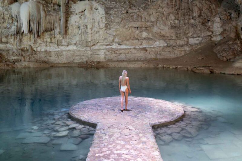 woman standing at the end of a pier inside Cenote Suytun near Chichen Itza Mexico
