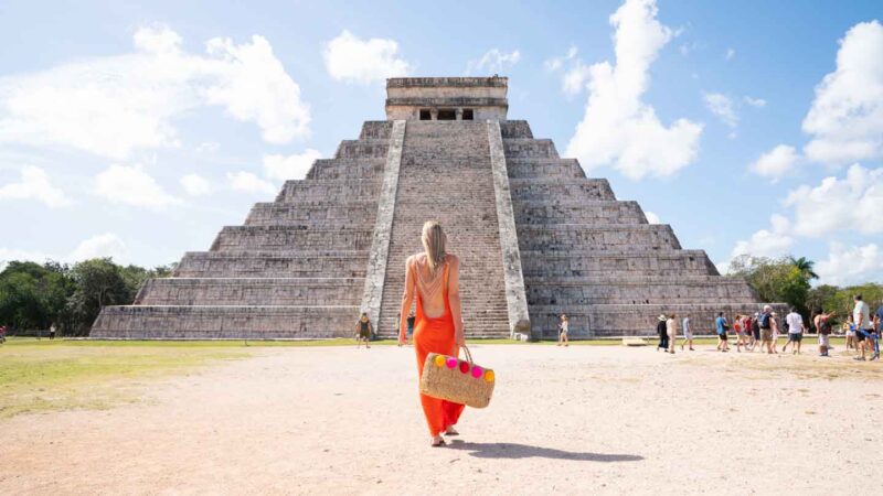 Woman standing in front of Chichen Itza in an orange dress