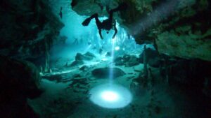 divingin Dos Ojos Cenote - Best cenotes in Tulum - Diver swimming with a flashlight during a cave dive