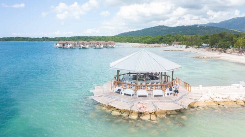 couple sitting in the hammocks of the Latitudes overwater bar at Sandals South Coast Resort