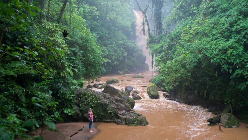 Woman standing infront of large waterfall in Costa Rica - La Paz Honeymoon Resort