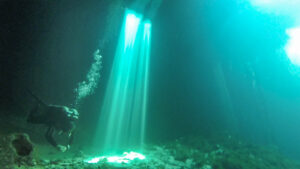 light beams in Cenote Calavera with a diver near