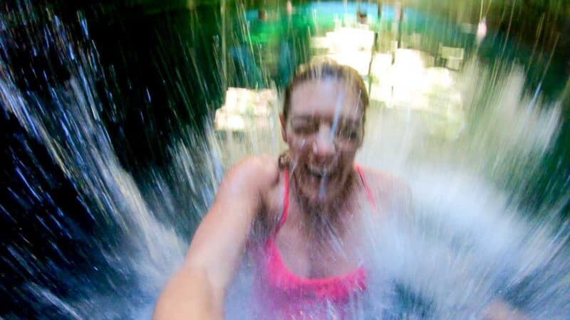 Woman jumping into Cenote Calavera making a splash from cliff jumping