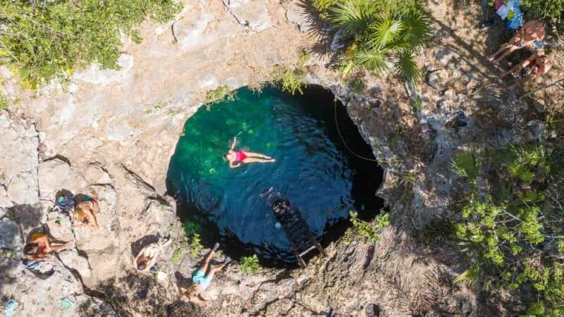 woman cliff jumping at Calavera Cenote - Tulum Mexico