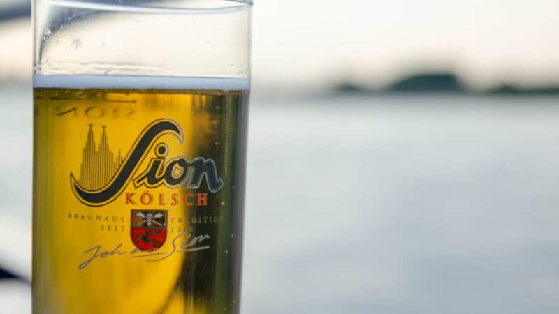 Kolsch style beer in the foreground with thee rhine river behind - Local style beer in Cologne Germany - must try things