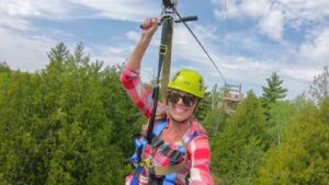 woman in a red shirt on a zip line tour in door county - things to do