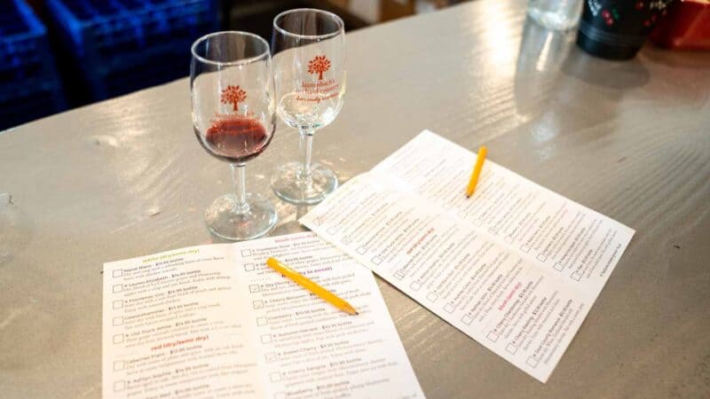 2 wine glasses in front of tasting menu at a Door County Winery - Things to do