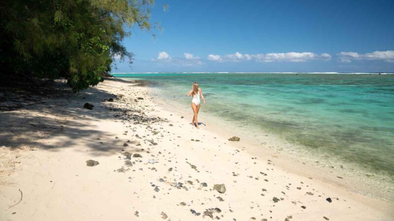 woman walking on one of the many beaches in Rarotonga - Top things to do