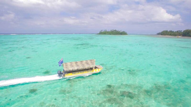 Bote amarillo con bandera de las islas de cocina conduciendo por la laguna en un crucero por la laguna de Rarotonga en Rarotonga - Actividad principal 