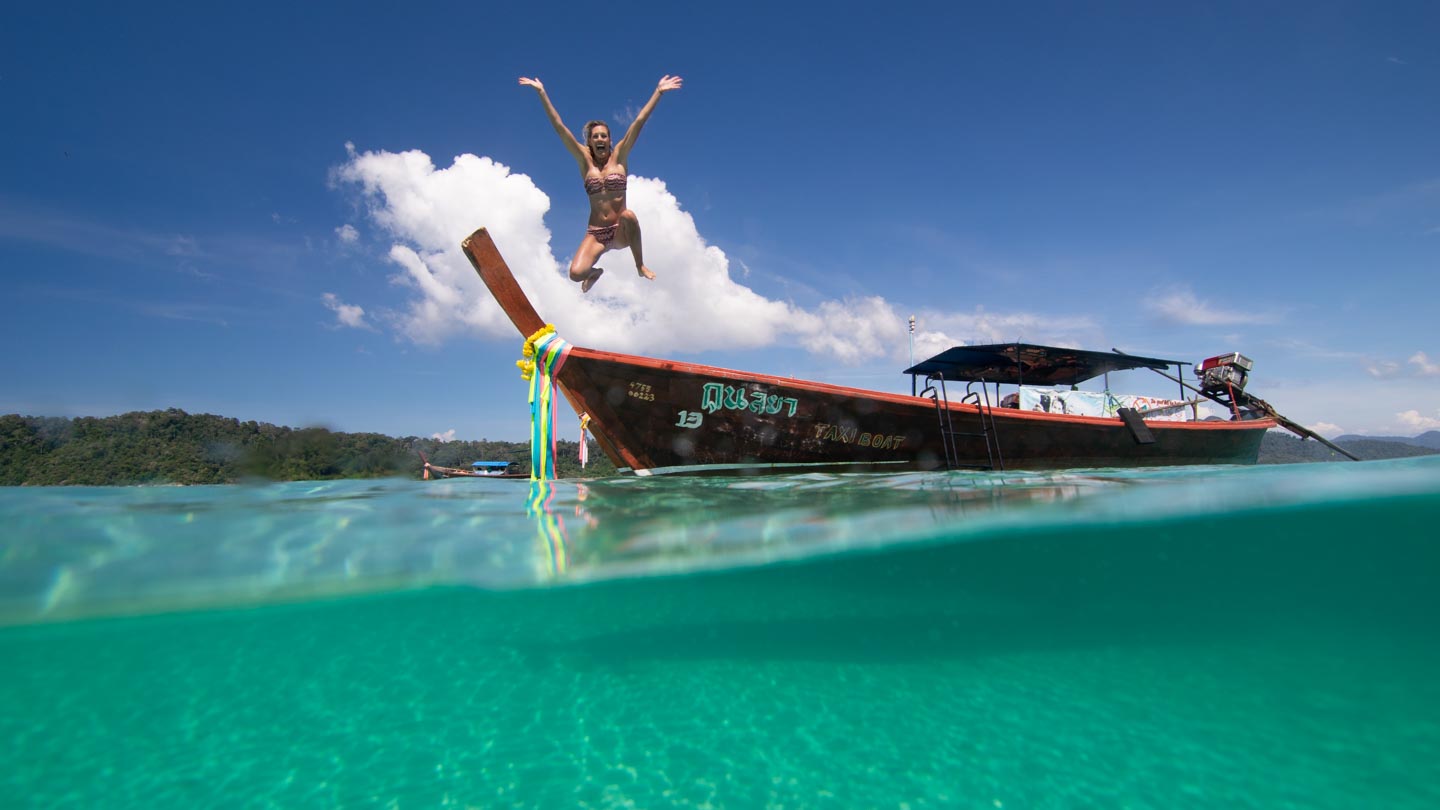 Woman jumping off of a Thai longtail boat in Koh Lipe