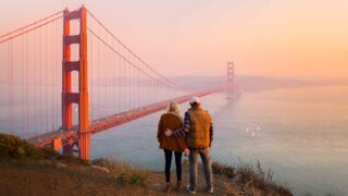 couple standing at Battery Spencer at sunset with views of the Golden Gate Bridge