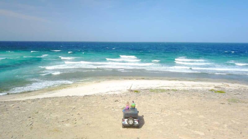 Couple sitting on top of their rental jeep in Cozumel - Do I need a Jeep in Cozumel