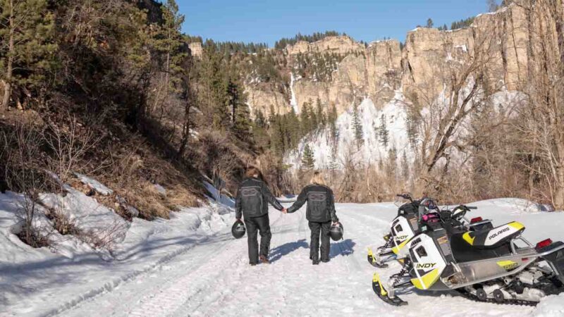 Couple holding hands walking on a snowmobile trail in Spearfish Canyon in the Black Hills of South Dakota