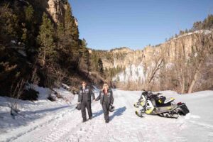 Couple walking toward the camera while holding hands on a snowmobile trail in South Dakota - Black Hills